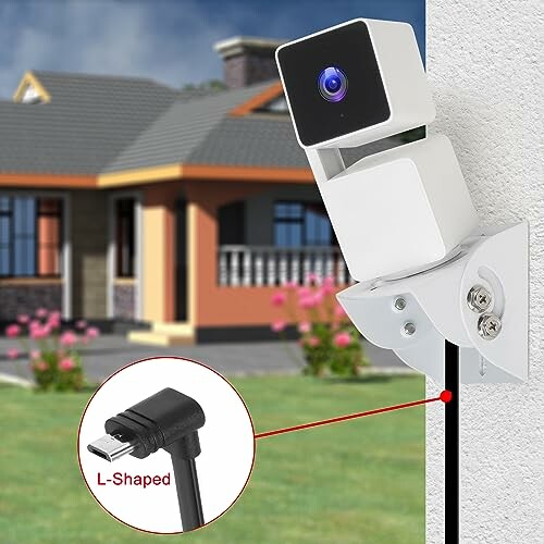 Outdoor security camera mounted on a house wall with L-shaped cable.